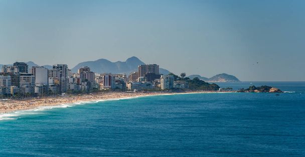 Παραλία Ipanema στη Βραζιλία σφύζει με τα πλήθη απολαμβάνοντας μια ηλιόλουστη μέρα του καλοκαιριού κάτω από μπλε ουρανό. - Φωτογραφία, εικόνα