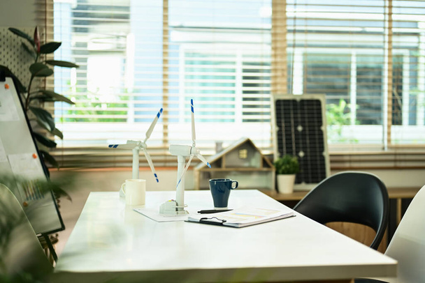 Modèles de moulins à vent et documents d'affaires sur table blanche au bureau. Concept d'énergie verte alternative. - Photo, image