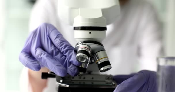 Closeup van microscoop en wetenschapper hand met microscoop in laboratorium. Opzetten van microscoop voor werkzaamheden - Video