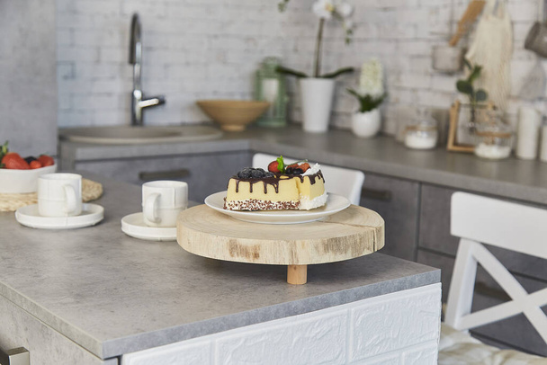 Modern kitchen breakfast setting with artificial cheesecake and fresh berries. - Photo, Image