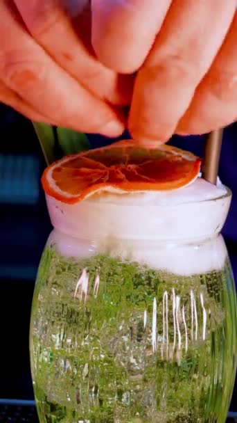 video verticale close-up girato barista preparazione di un cocktail verde con guarnire frutta. Vita notturna stile di vita, alcol, club - Filmati, video