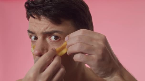 Iso lähikuva gen Y mies soveltamalla silmien alla hunaja laikkuja samalla hoitaa ihoa - Materiaali, video