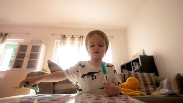 En este video, se puede ver a un niño sentado en una mesa mientras sostiene un cepillo de dientes en su boca. - Imágenes, Vídeo