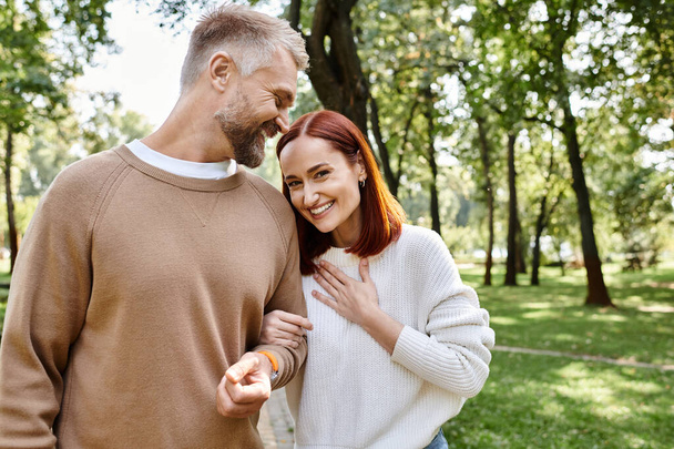 Un homme et une femme en tenue décontractée debout ensemble dans un parc paisible. - Photo, image