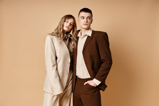 appealing young man in debonair suit posing next to his beautiful girlfriend who looking at camera - Zdjęcie, obraz