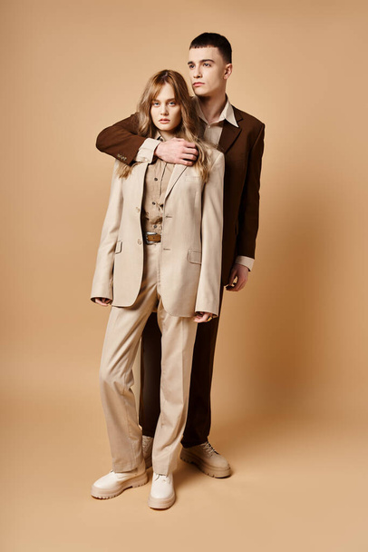 good looking man in debonair suit posing next to his beautiful girlfriend who looking at camera - Foto, Imagen