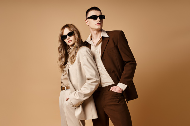 appealing elegant couple in chic seasonal suits with stylish sunglasses posing on pastel background - Foto, Imagem