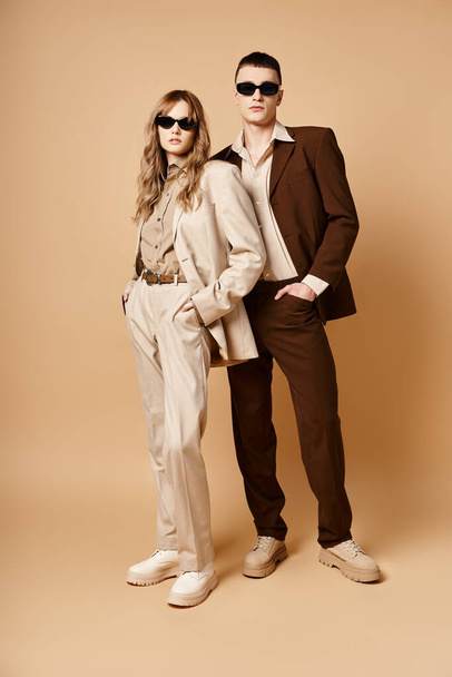 attractive elegant couple in chic seasonal suits with stylish sunglasses posing on pastel background - Foto, afbeelding