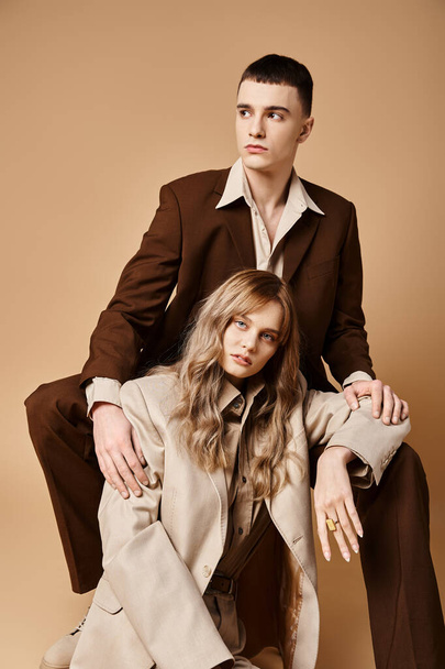 appealing young woman in pastel suit looking at camera sitting next to her handsome boyfriend - Foto, imagen