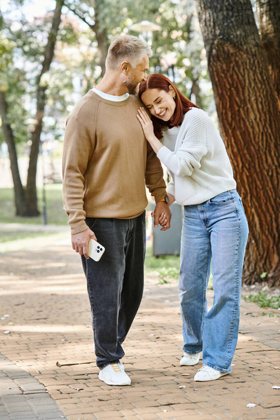 Ενήλικες ερωτευμένοι ζευγάρι σε casual ενδυμασία στέκεται μαζί στο πάρκο. - Φωτογραφία, εικόνα