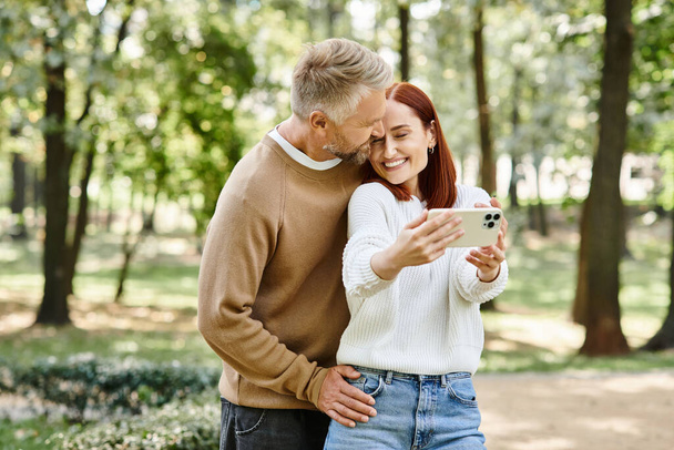 A man and woman in casual attire engaged with a cell phone. - Photo, Image