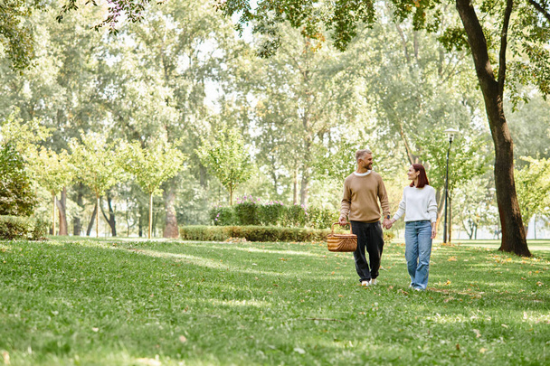 Kochająca się para w luźnym stroju spokojnie spaceruje po spokojnym parku. - Zdjęcie, obraz