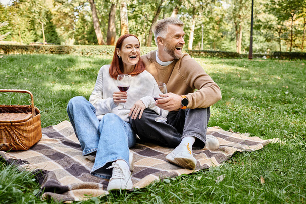 Mies ja nainen rentoutuvat huopalla nurmikolla puistossa.. - Valokuva, kuva