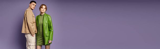 stilvolles Liebespaar in lebendiger Kleidung posiert gemeinsam vor violettem Hintergrund und blickt in die Kamera - Foto, Bild