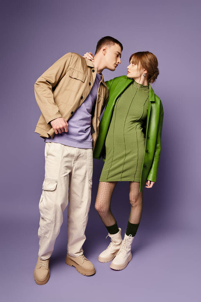 verleidelijk liefdevol paar in levendige kleurrijke kledij kijken naar elkaar op paarse achtergrond - Foto, afbeelding