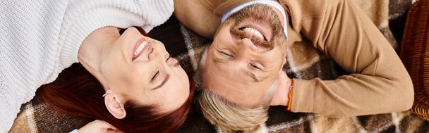 Мужчина и женщина мирно лежат на одеяле в парке. - Фото, изображение