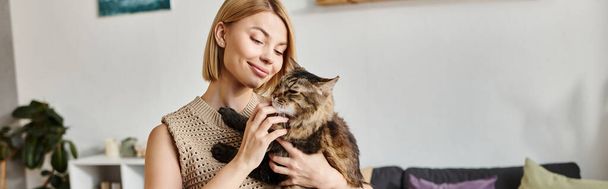 Een aantrekkelijke vrouw met kort haar wiegt een kat in haar handen, het tonen van de band tussen mens en katachtige. - Foto, afbeelding