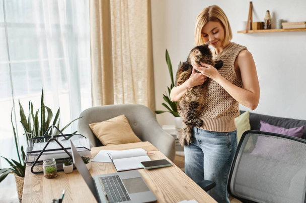 Kısa saçlı bir kadın bir kediyi nazikçe elinde tutuyor, evinde bir anlık bağ ve rahatlık sergiliyor.. - Fotoğraf, Görsel