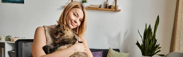 短髪の女性は喜んで自宅で暖かい抱擁で彼女の猫を抱擁しています. - 写真・画像