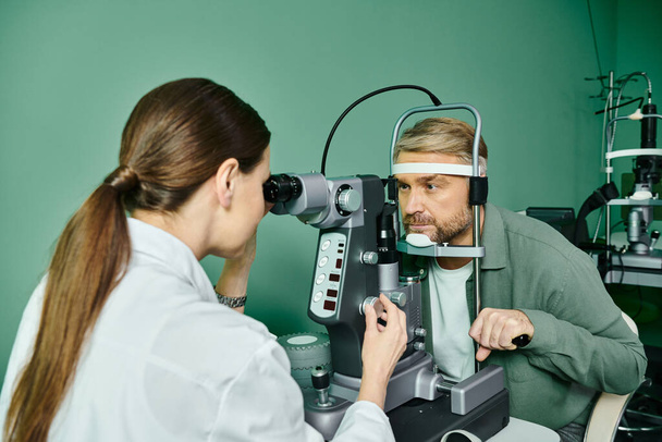 Ansprechender Arzt bei der Augenuntersuchung im professionellen Umfeld. - Foto, Bild