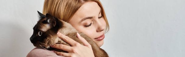 Eine Frau mit kurzen Haaren hält ihre Katze liebevoll dicht vor ihrem Gesicht und fördert ein Band der Zuneigung und Ruhe. - Foto, Bild