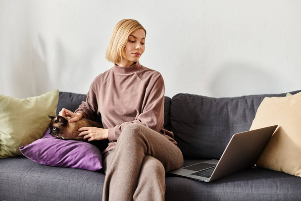 Mujer con el pelo corto sentado en el sofá, vinculándose con el gato en su regazo. Ambiente hogareño, relajado y alegre. - Foto, imagen