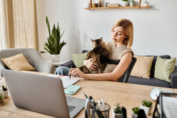 Een vrouw met kort haar zit aan een tafel, zachtjes een kat in haar schoot houdend, beide in een vredig moment thuis. - Foto, afbeelding
