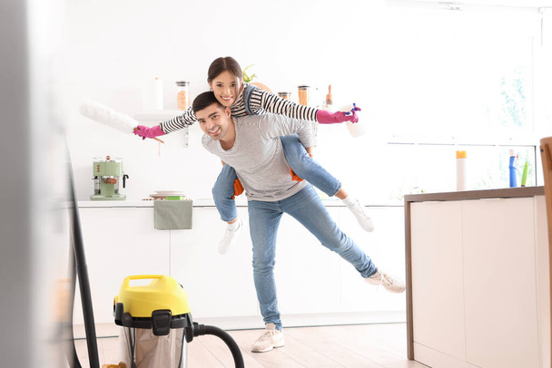 Feliz joven pareja divirtiéndose mientras limpia en la cocina - Foto, Imagen