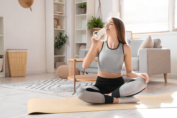 Sportos fiatal nő iszik ízletes joghurtot otthon - Fotó, kép