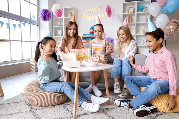Lindos niños pequeños en sombreros de fiesta con pastel celebrando el cumpleaños en casa - Foto, Imagen