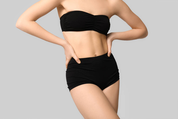 Sexy jonge vrouw in zwart ondergoed op lichte achtergrond - Foto, afbeelding