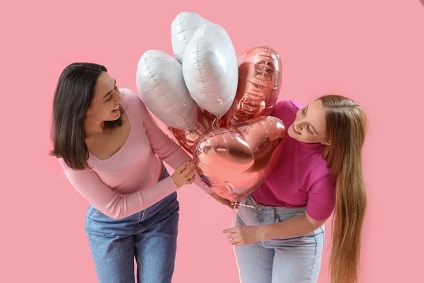 Jovem casal lésbico com balões no fundo rosa. Celebração do Dia dos Namorados - Foto, Imagem