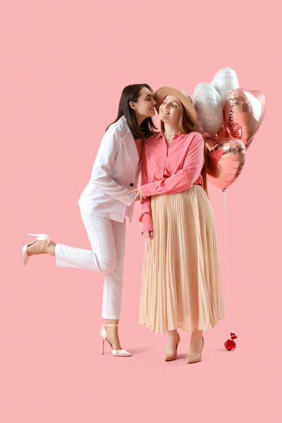 Молодая лесбийская пара с шариками на розовом фоне. Празднование Дня Святого Валентина - Фото, изображение