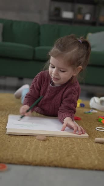 Ένα κορίτσι καυκάσιος νήπιο παίζουν στο πάτωμα στο σπίτι κλήρωση με στυλό - Πλάνα, βίντεο