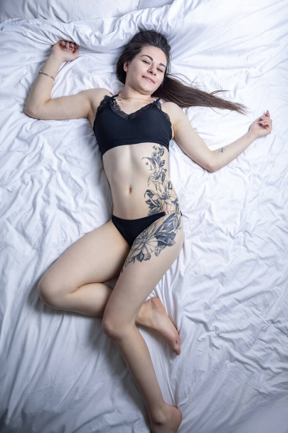 Kyjev, Ukrajina - 5. února. 2024 Dívka s tetováním na posteli. - Fotografie, Obrázek