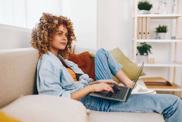 Mujer sonriente usando un ordenador portátil en una acogedora oficina en casa, abrazando el estilo de vida moderno freelance - Foto, imagen