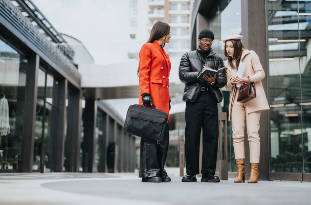 A diverse trio of professionals engaged in a conversation on a city street, showcasing a modern business casual lifestyle. - Photo, Image