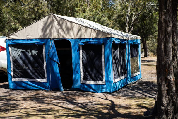 namioty i przyczepy kempingowe kempingowe na odosobnionym kempingu z niebieskim namiotem - Zdjęcie, obraz