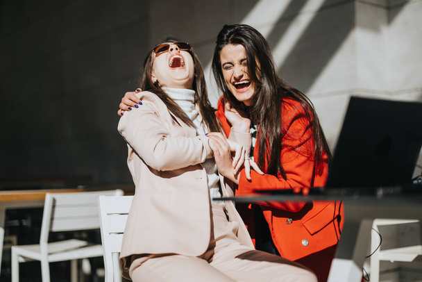 Due donne d'affari gioiose ridono insieme durante un incontro informale fuori. - Foto, immagini