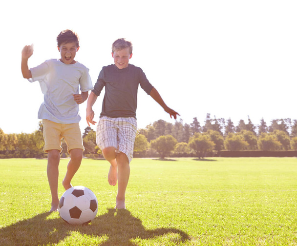 Piłka nożna, przyjaciele i szczęśliwy do gry na trawie, wsparcie i uśmiech do gry sportowej na boisku. Chłopcy, dzieci i występy na boisku zewnętrznym, zacieśnianie więzi i śmiech dla rywalizacji lub wyzwania. - Zdjęcie, obraz