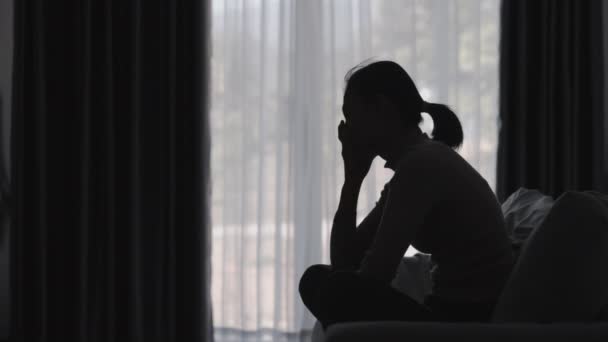 Silhouette de la femme souffrant de dépression se trouve sur le canapé, a le stress, l'anxiété, la maladie et les maux de tête, les problèmes de vie, la violence familiale, la santé mentale, les pensées de suicide.  - Séquence, vidéo