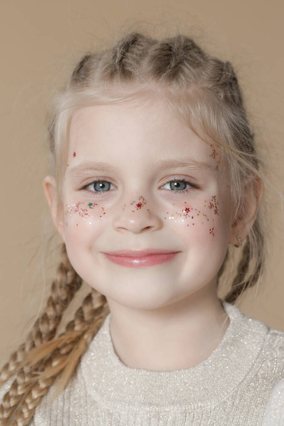 Retrato de linda niña rubia con trenzas de boxeador y purpurina cara om - Foto, imagen