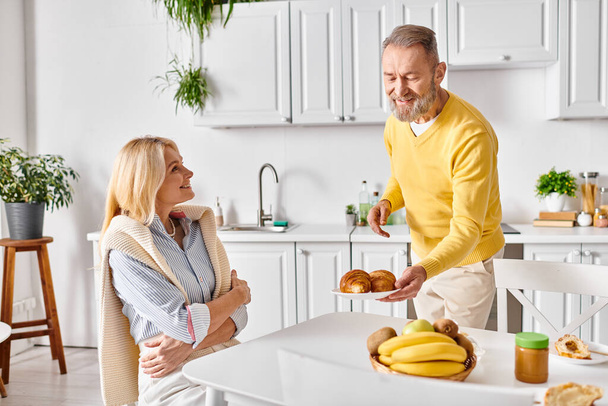 Bir erkek ve bir kadın samimi ev kıyafetleri içinde mutfakta birlikte durur, sevgi ve aile içi aktivitelerle meşgul olurlar.. - Fotoğraf, Görsel