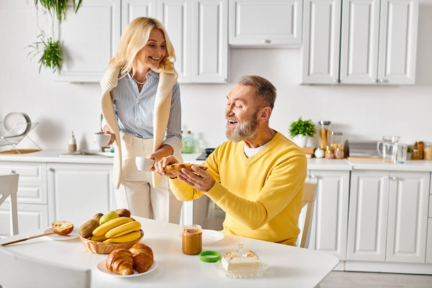 Мужчина и женщина в уютной домашней одежде сидят за столом, разделяя момент связи и партнерства, когда они проводят время вместе. - Фото, изображение