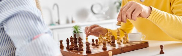 Kypsä rakastava pari viihtyisissä kotivaatteissa keskittyi syvästi shakkipeliin, pohtien seuraavia liikkeitään.. - Valokuva, kuva