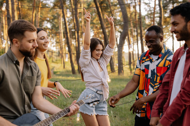 Multirassische Gruppe von Menschen, schöne Hipsterfrau, die auf dem Hintergrund von Freunden tanzt, die Spaß haben - Foto, Bild