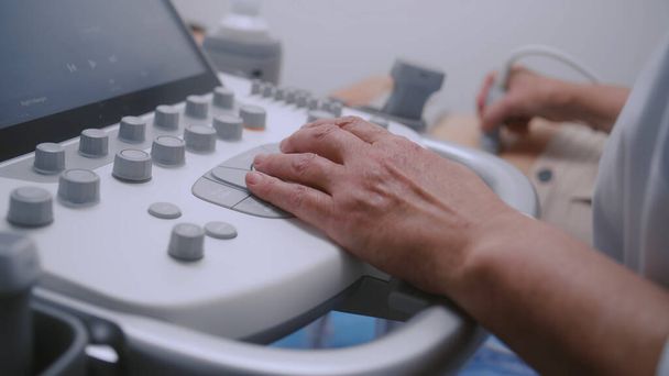 Κοντινό πλάνο του γιατρού χρησιμοποιώντας μηχάνημα υπερήχων με ψηφιακή οθόνη. Επαγγελματίας γιατρός εκτελεί υπερηχογράφημα κοιλιακών οργάνων μέχρι γυναίκα ασθενή. Σύγχρονη κλινική ή νοσοκομείο με προηγμένο εξοπλισμό. - Φωτογραφία, εικόνα