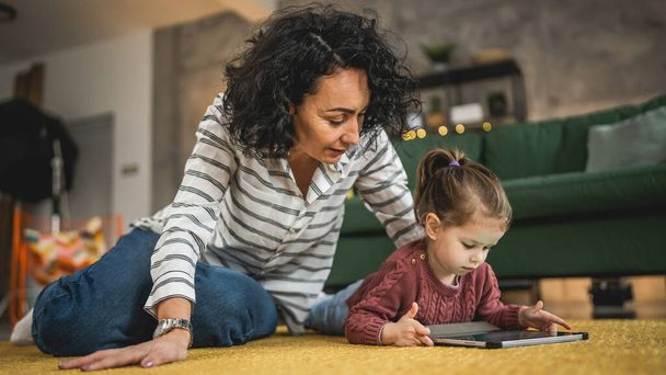Madre e figlia utilizzano tablet digitale per guardare video online a casa - Foto, immagini