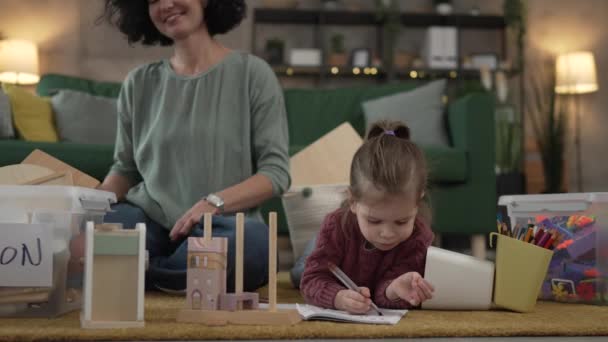 moeder en dochter peuter meisje thuis kiezen speelgoed voor donatie - Video