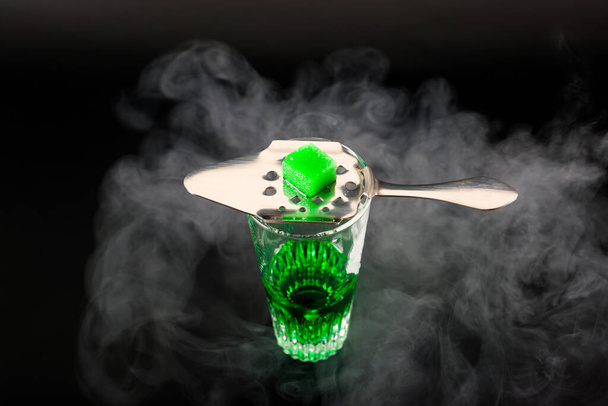 Beyaz şeker küplü özel bir kaşıkla servis edilen Absinthe adlı yeşil aromalı votka. - Fotoğraf, Görsel